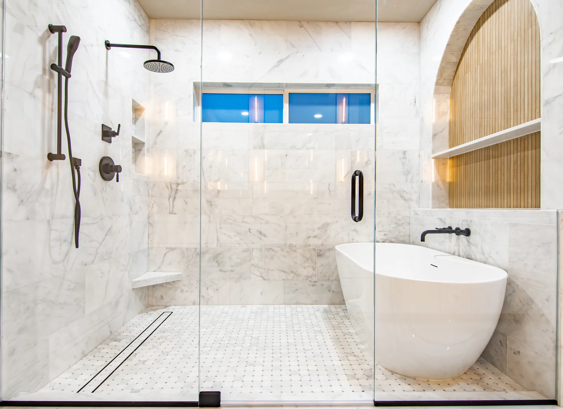 Custom tiled walk-in shower by Hometown Stone with large-format surround, mosaic pan, built-in bench, and frameless glass