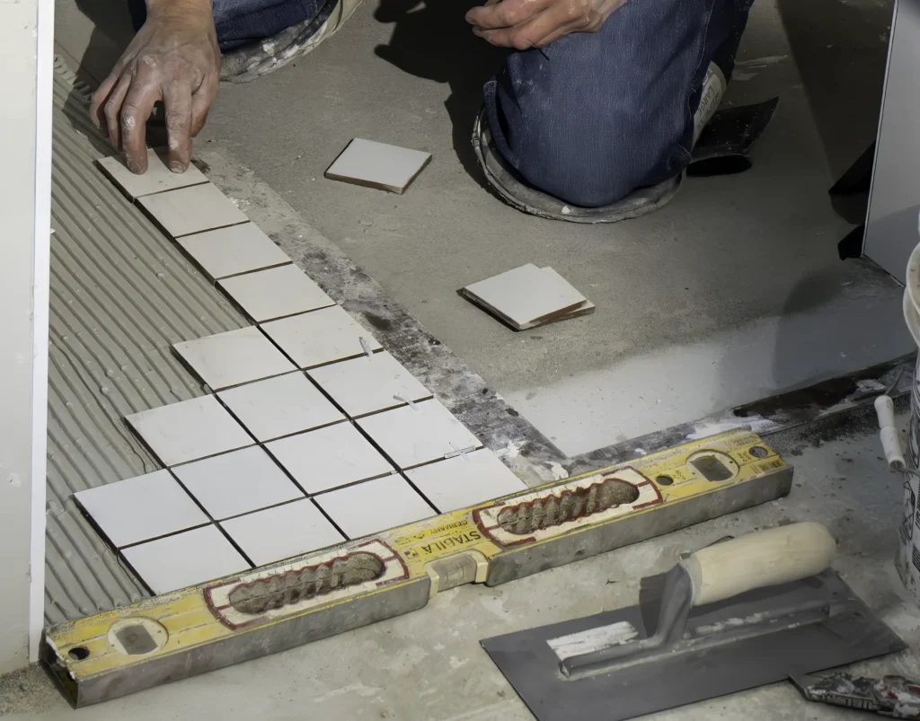 Close-up of professional tile setter installing square tiles with leveling tools by Hometown Stone.