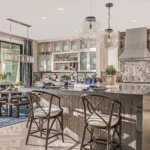 Open-concept kitchen with waterfall stone island, custom stone backsplash, and patterned tile flooring by Hometown Stone.